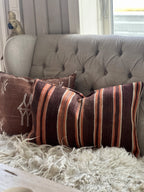 Kelimpute 40x60 cm i brune og oransje striper på grå sofa med saueskinn